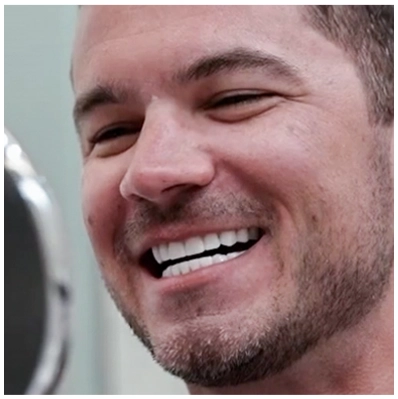 A patient smiling broadly as they look at their new smile in the mirror after their dental crown procedure.