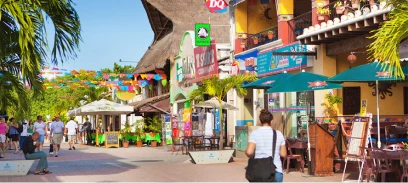 Colorful street in Playa del Carmen with shops and pedestrians.