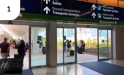 Cancun Airport terminal exit with signs for ground transportation..
