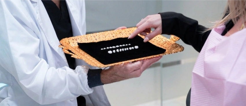 Dentist showing veneers shade guide to patient, choosing porcelain veneers color, cosmetic dentistry consultation, smile makeover planning, dental veneers selection process